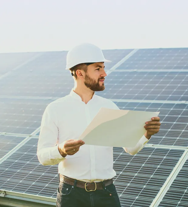Técnico revisando planos frente a una planta solar